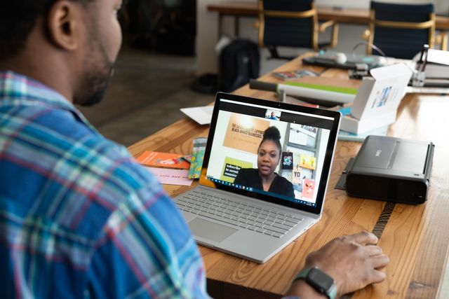 Person on a laptop video call at a home desk